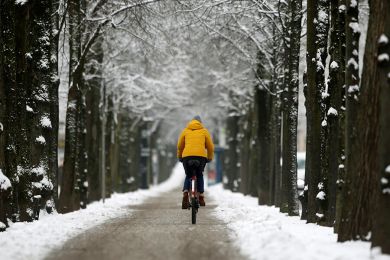 Fahrradfahrerin fährt auf einem Radweg im Winter. 
