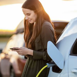 Eine junge Frau lädt ihr Elektroauto auf einem öffentlichen Parkplatz.