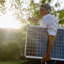 Ein Mann trägt eine Mini-Solaranlage zu seinem Haus.