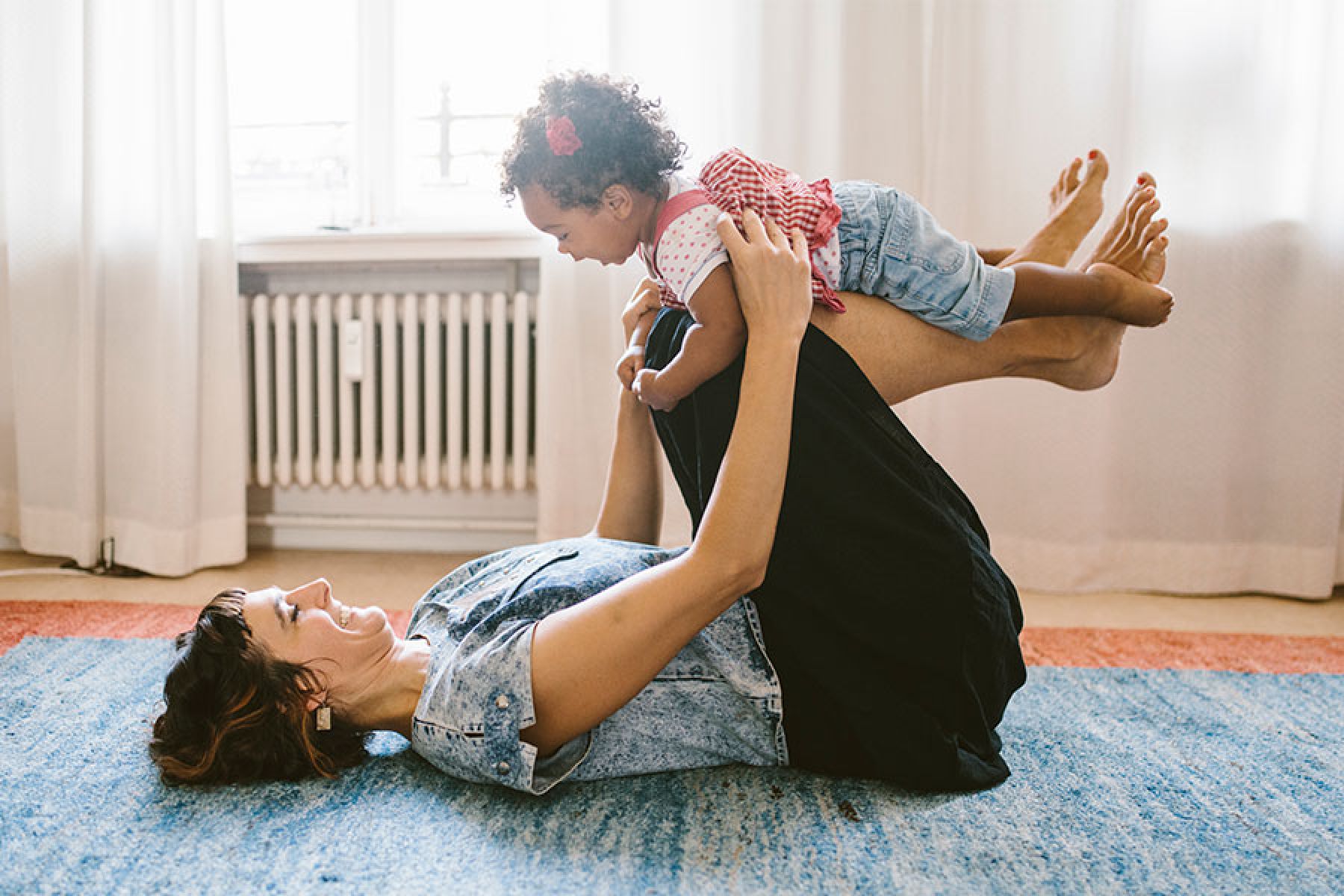 Eine Mutter und ihr Baby turnen auf dem Fußboden.