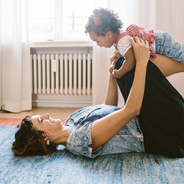 Eine Mutter und ihr Baby turnen auf dem Fußboden.