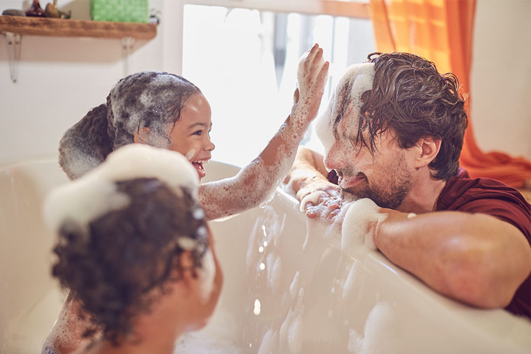 Zwei Kinder planschen in der Badewanne.