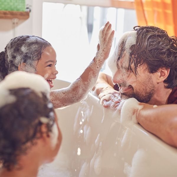 Zwei Kinder planschen in der Badewanne.
