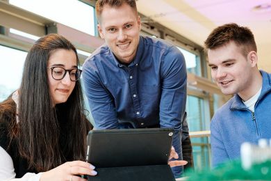 Drei Auszubildenden von enercity schauen zusammen auf ein Tablet. 