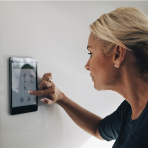 Eine Frau regelt die Zimmertemperatur über ein smartes Thermostat.