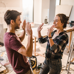 Glückliches Paar geben sich high-five beim Renovieren ihres Hauses.  