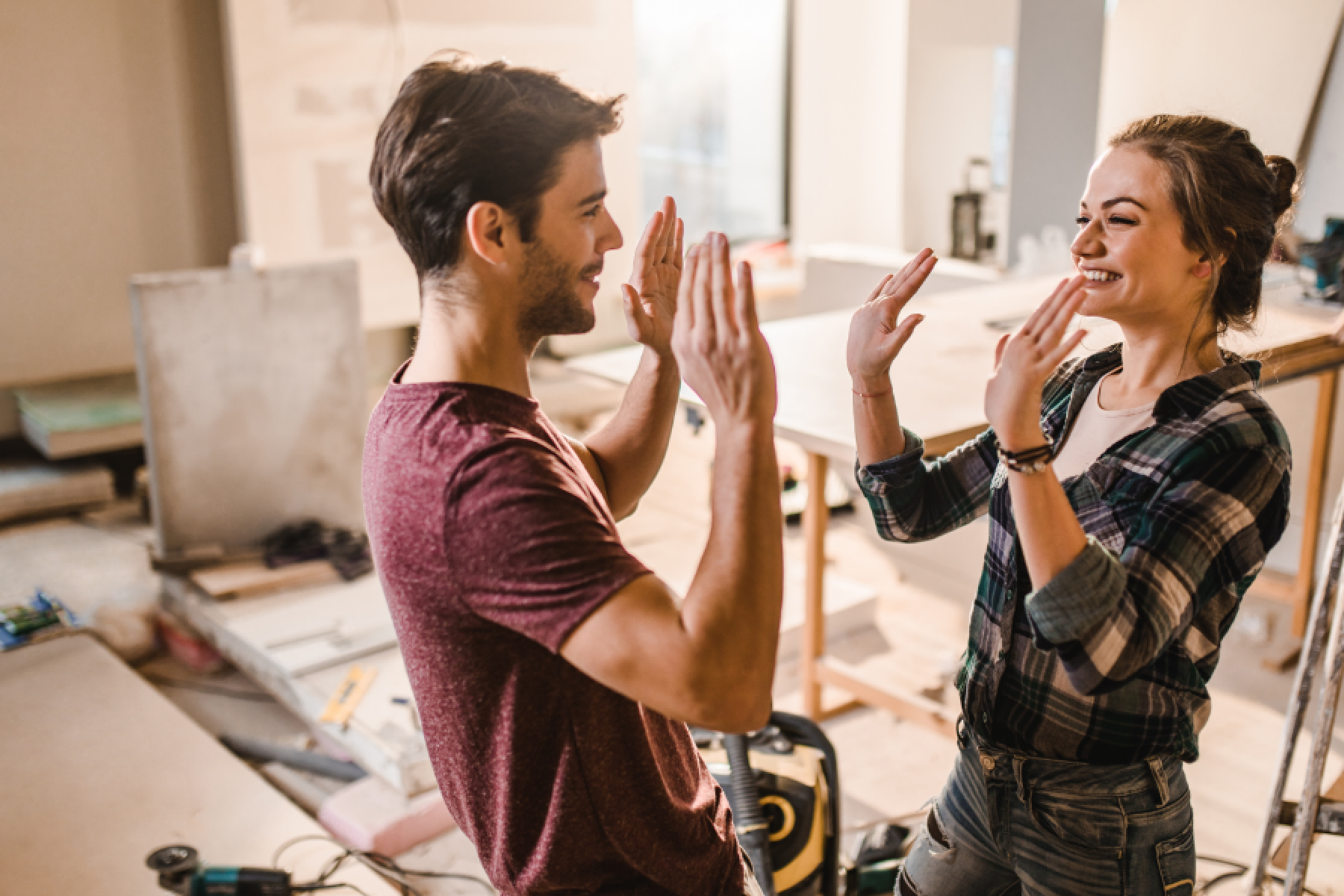 Glückliches Paar geben sich high-five beim Renovieren ihres Hauses.  
