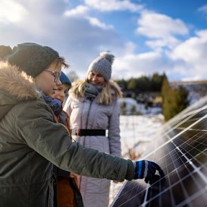 Mutter erklärt den Kindern an einem Wintertag die Technologie der Son-nenkollektoren.