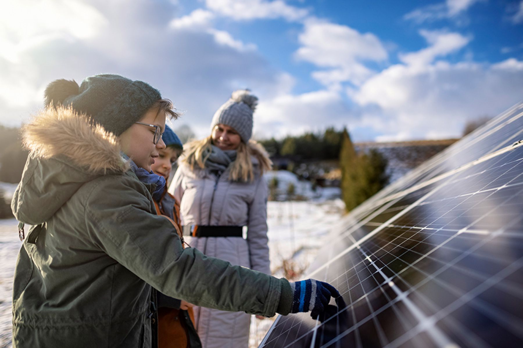 Mutter erklärt den Kindern an einem Wintertag die Technologie der Son-nenkollektoren.