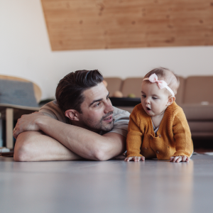 Vater und Tochter liegen im Wohnzimmer auf dem Fußboden. 