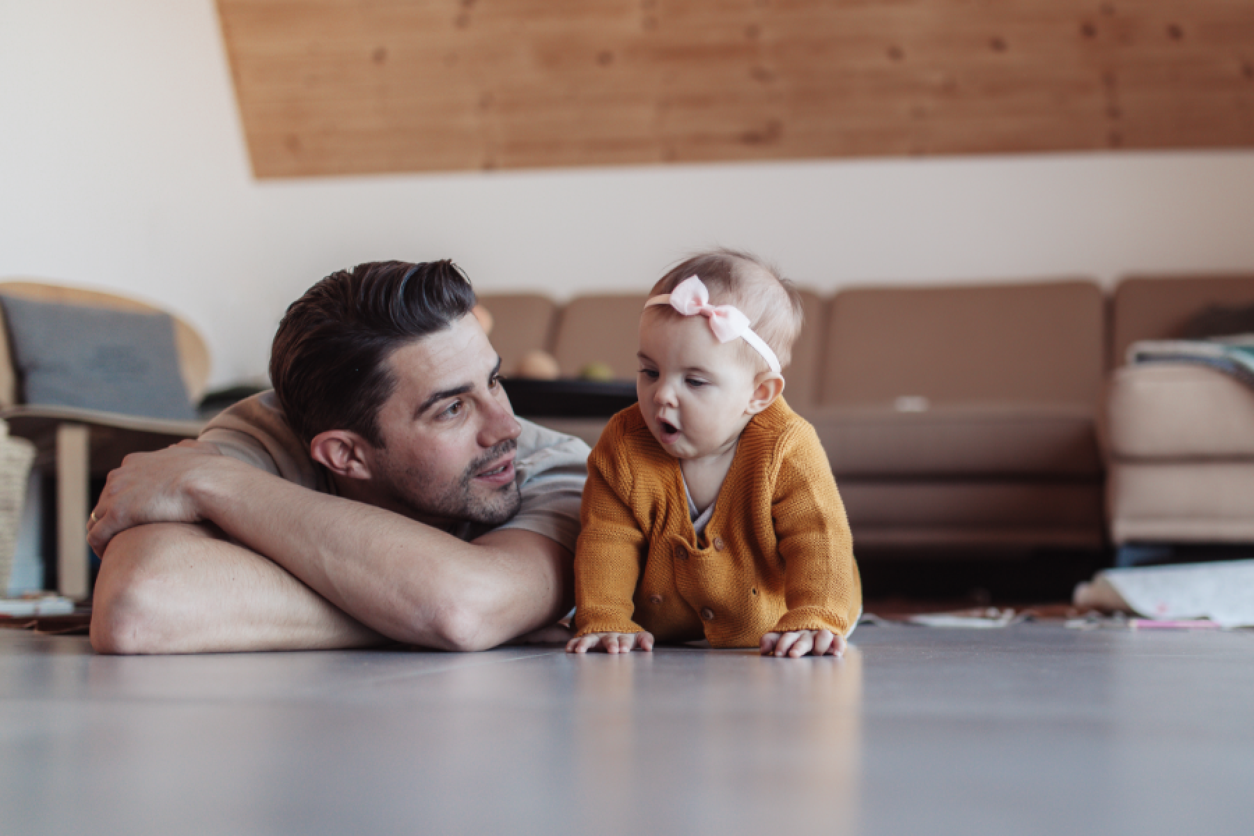Vater und Tochter liegen im Wohnzimmer auf dem Fußboden. 