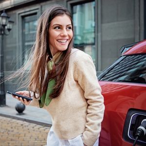 Eine junge Frau lädt ihr Elektroauto auf. 