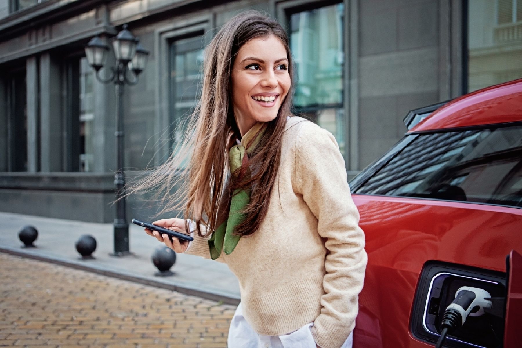 Eine junge Frau lädt ihr Elektroauto auf. 