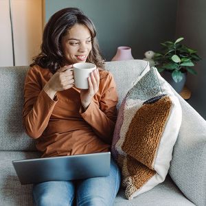 Eine Frau sitzt auf dem Sofa, das in der Nähe der Heizung steht, und liest ein Buch. 