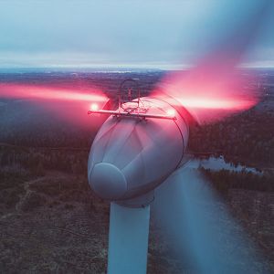 Nächtlicher Blick auf eine beleuchtete Windenergieanlage. 