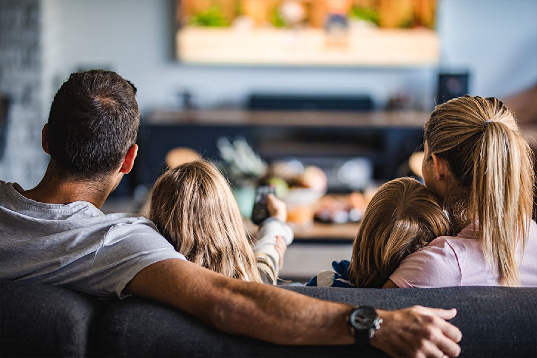 Eine Familie sitzt auf dem Sofa und sieht fern.