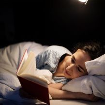 Frau liegt im Bett und liest.