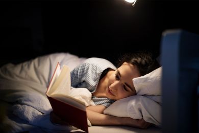 Frau liegt im Bett und liest.