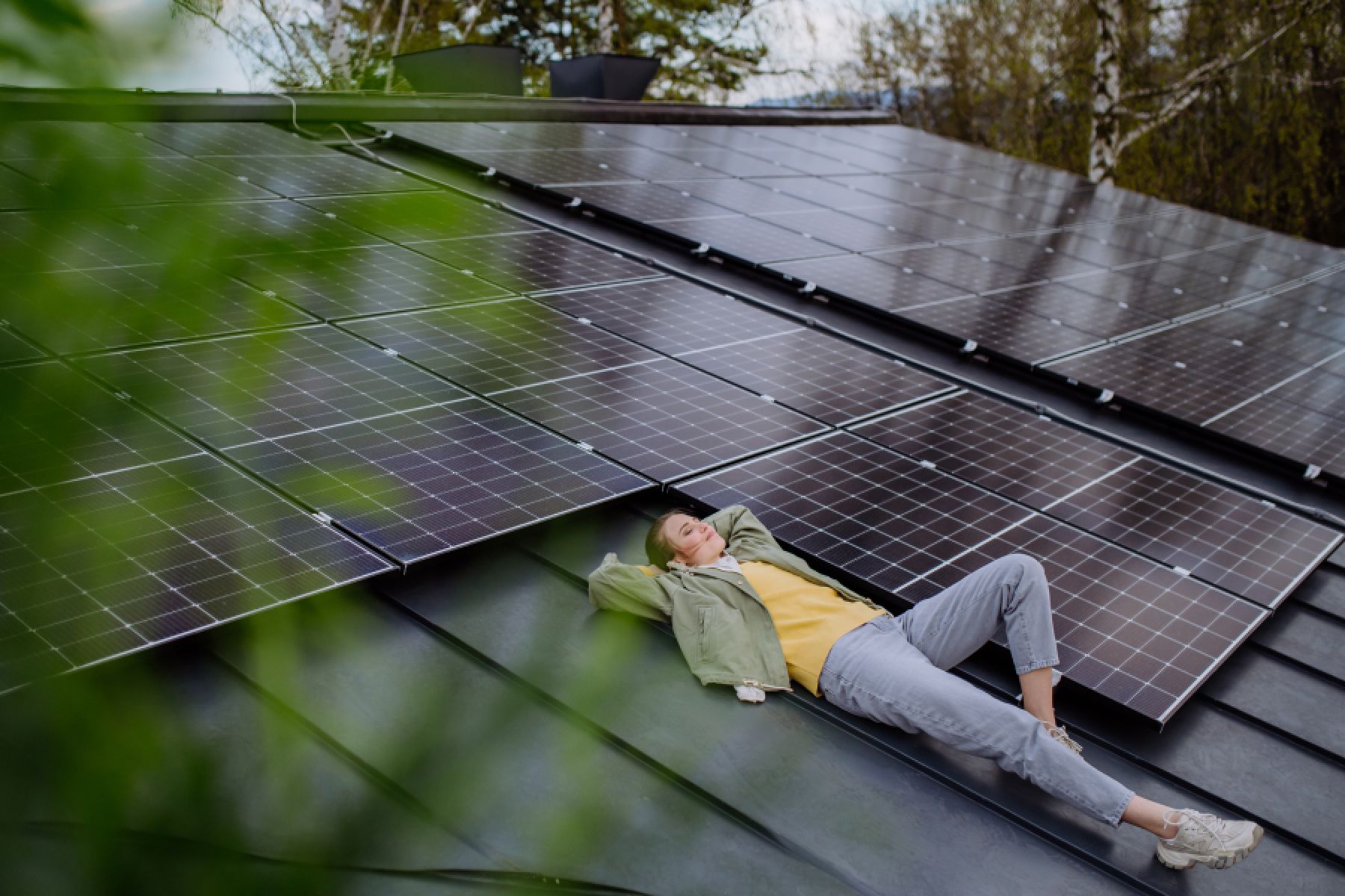 Ein junge Frau liegt auf einem Dach, umgeben von Solarpanels. 