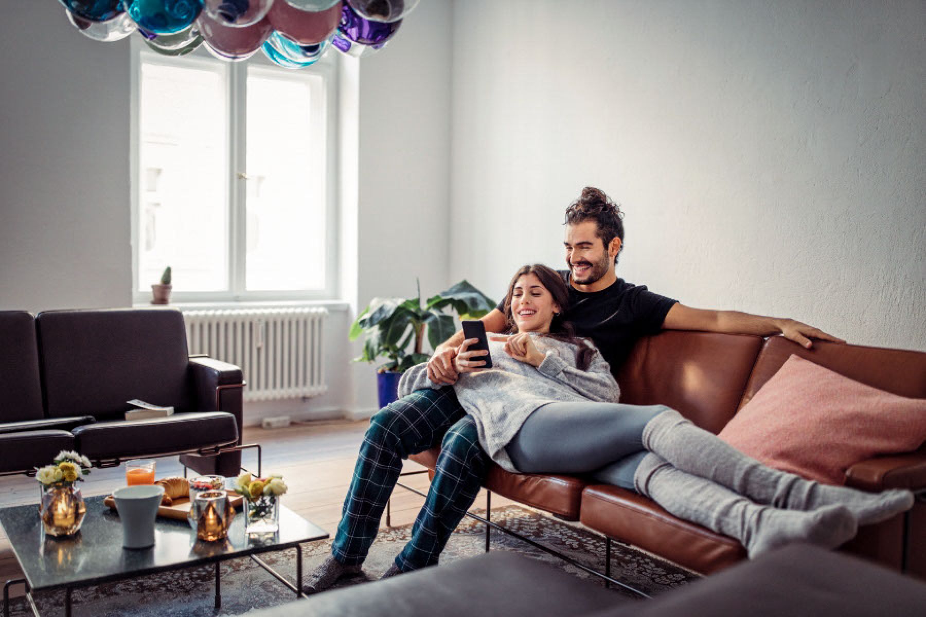 Ein junges Paar sitzt im Wohnzimmer auf dem Sofa. 