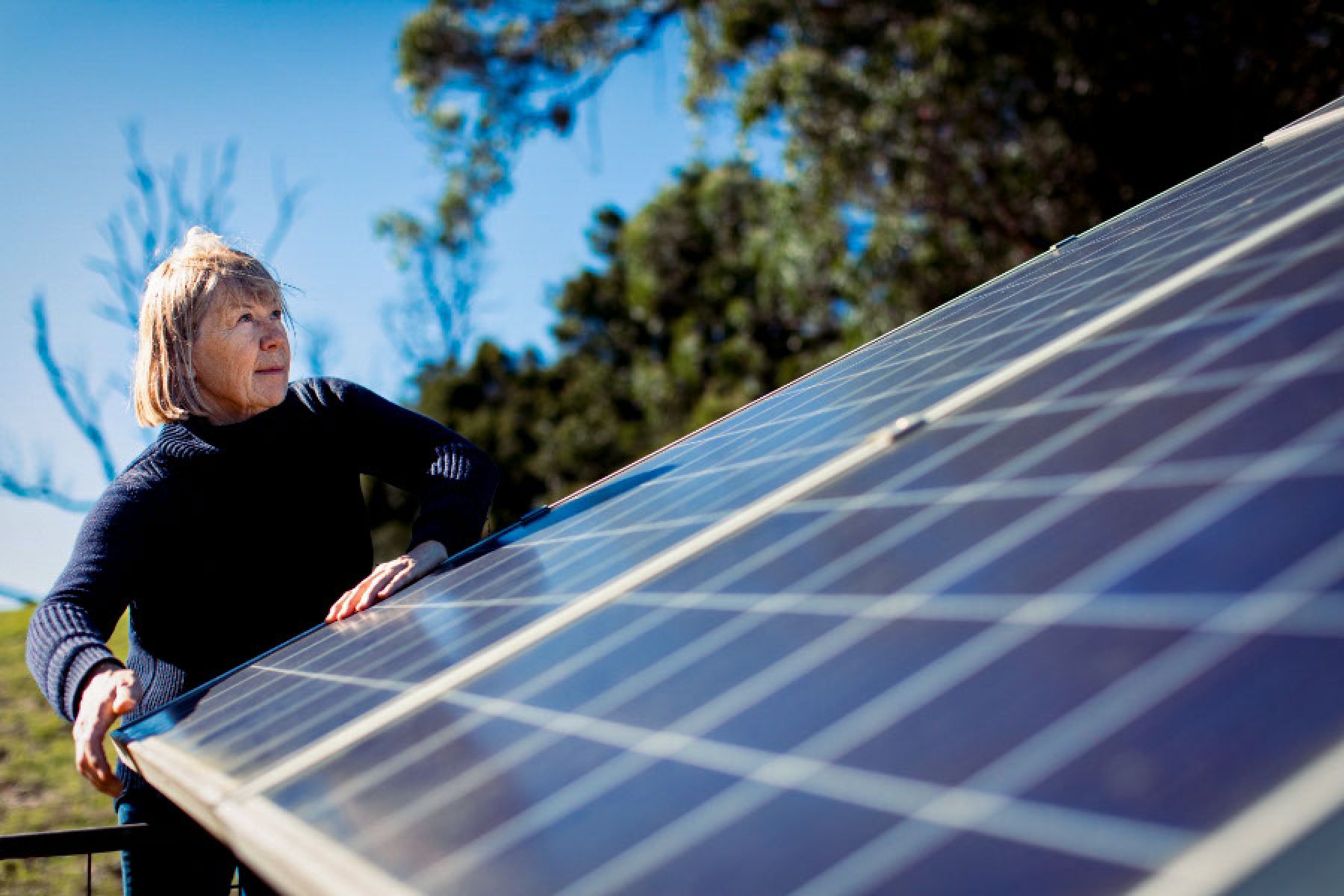 Eine Frau überprüft in ihrem Garten ein Solarpanel. 