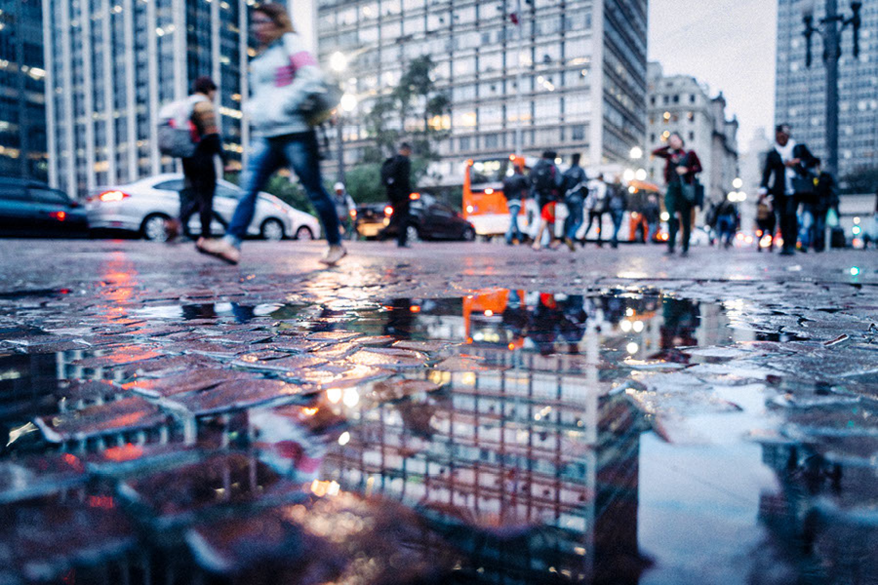 Eine Straßenszene wird in einer Pfütze reflektiert.