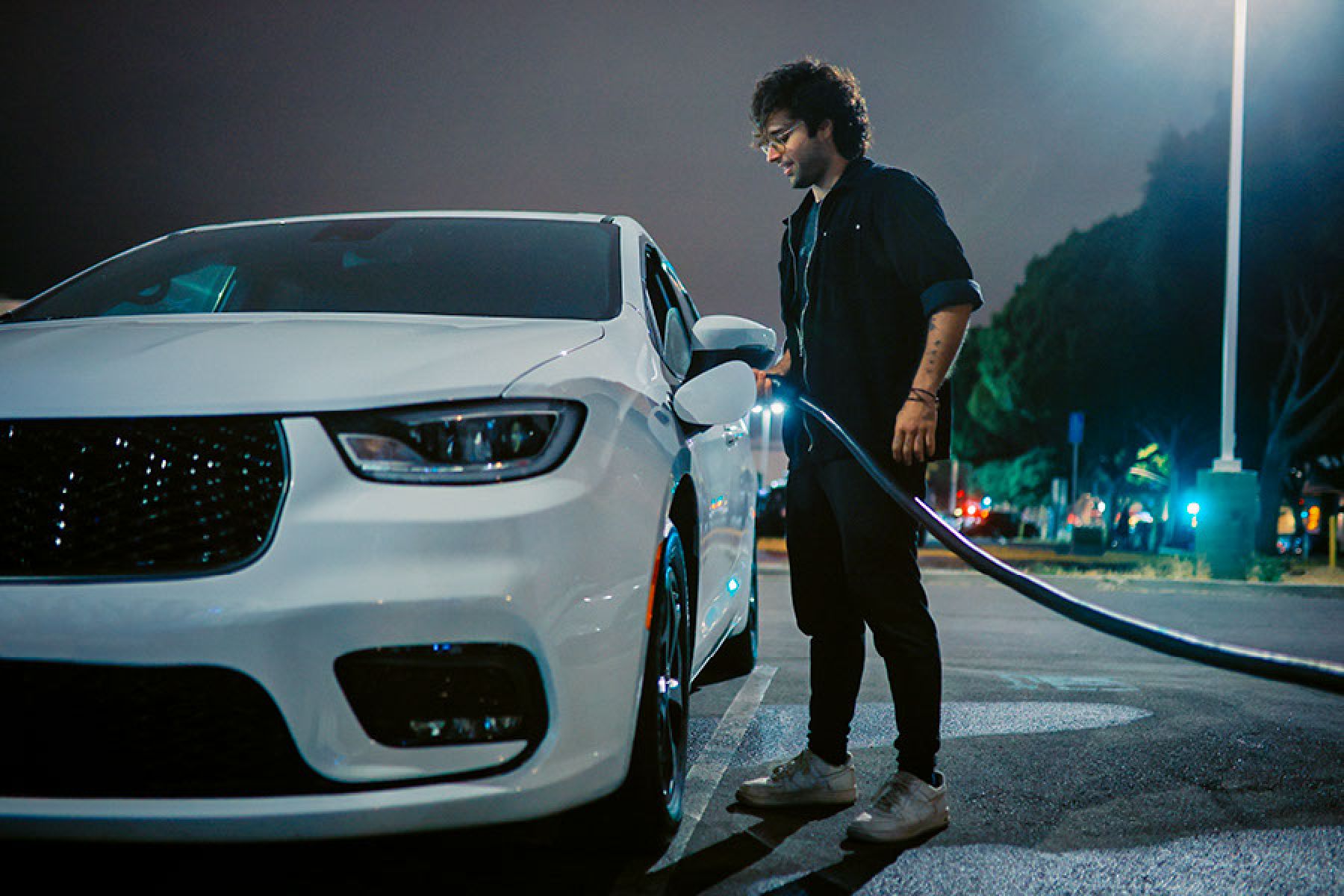 Ein Mann steht an seinem E-Fahrzeug und lädt es auf.