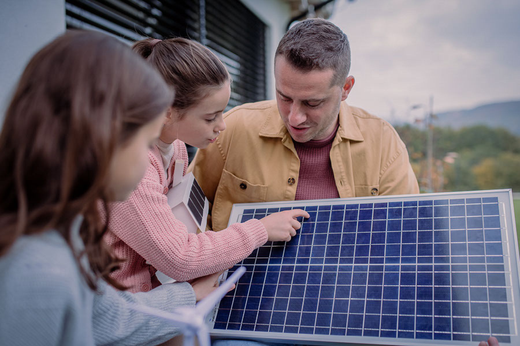 Ein Vater erklärt seinen beiden Kindern, wie ein Solarpanel aufgebaut ist. 