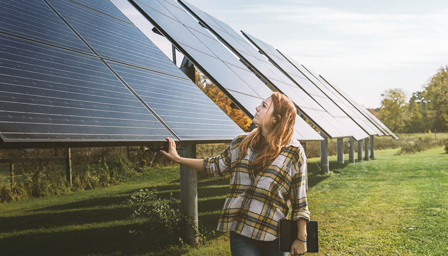 Agri- und Floating-PV-Anlagen leisten einen Beitrag zur erneuerbaren Energieerzeugung. Eine Frau begutachtet die Solarmodule einer Agri-PV-Anlage.