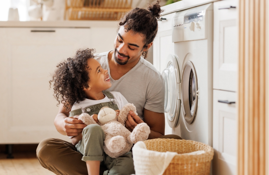 Sohn hilft dem Vater, die Waschmaschine zu befüllen.