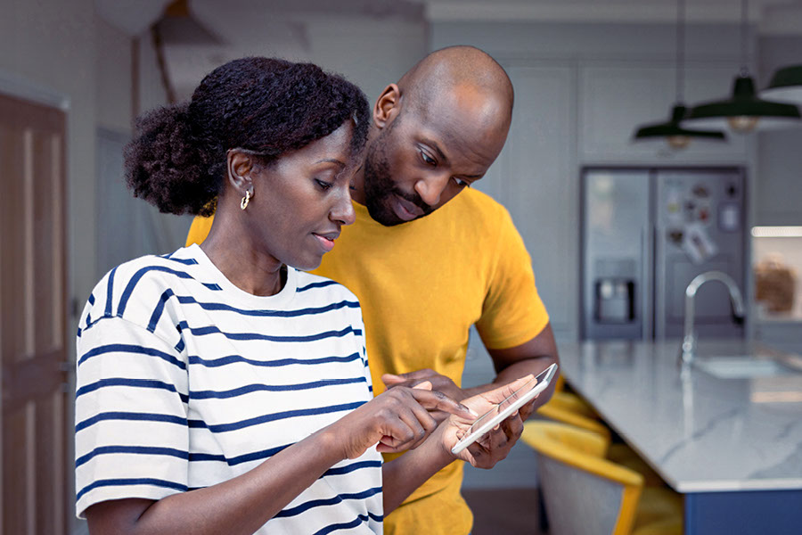 Ein junges Paar, das sein Smart Home von einem Tablet aus steuert.