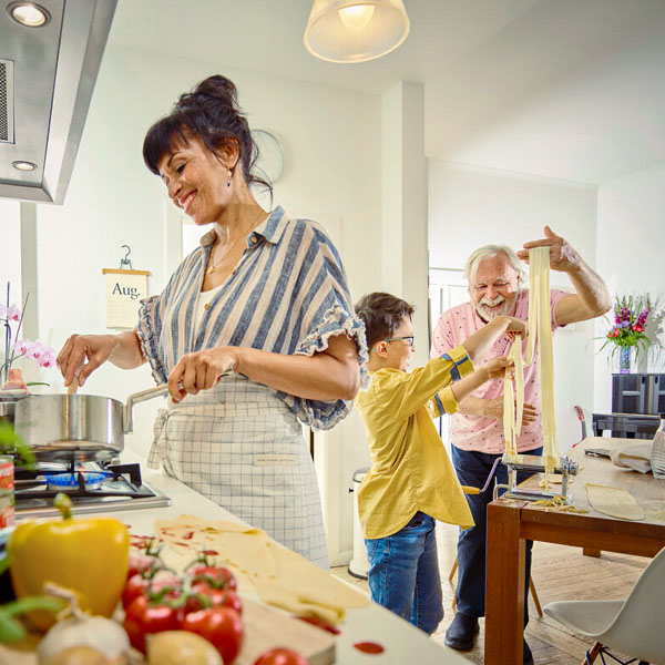 Eine Familie kocht in der Küche selbstgemachte Nudeln.