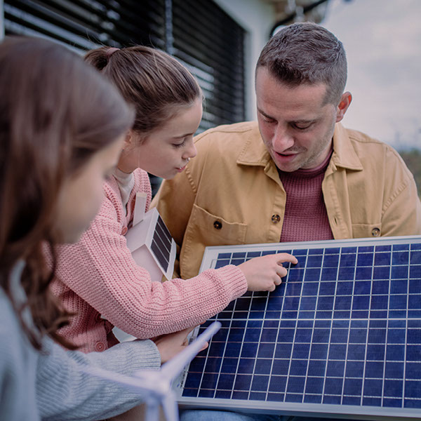 Ein Vater erklärt seinen beiden Kindern, wie ein Solarpanel aufgebaut ist. 
